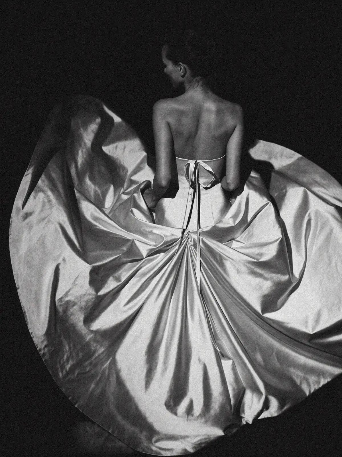 Bride seen from behind in ivory duchesse satin, the skirt thrown open in a full circle