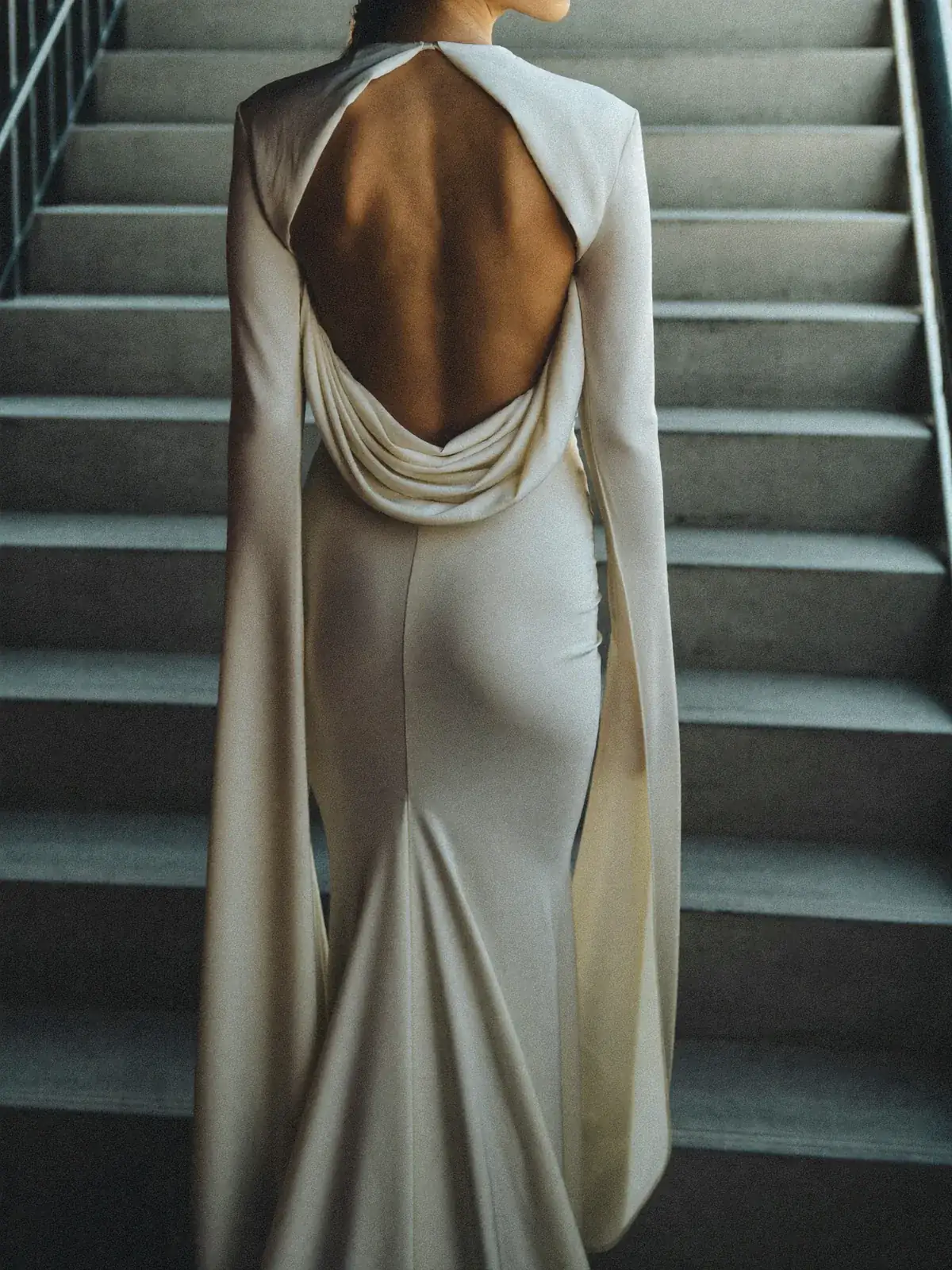 Bride from behind on a concrete stair in silk gazar with an open structured back